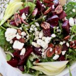 beet salad in bowl topped with pecans and feta cheese crumbles
