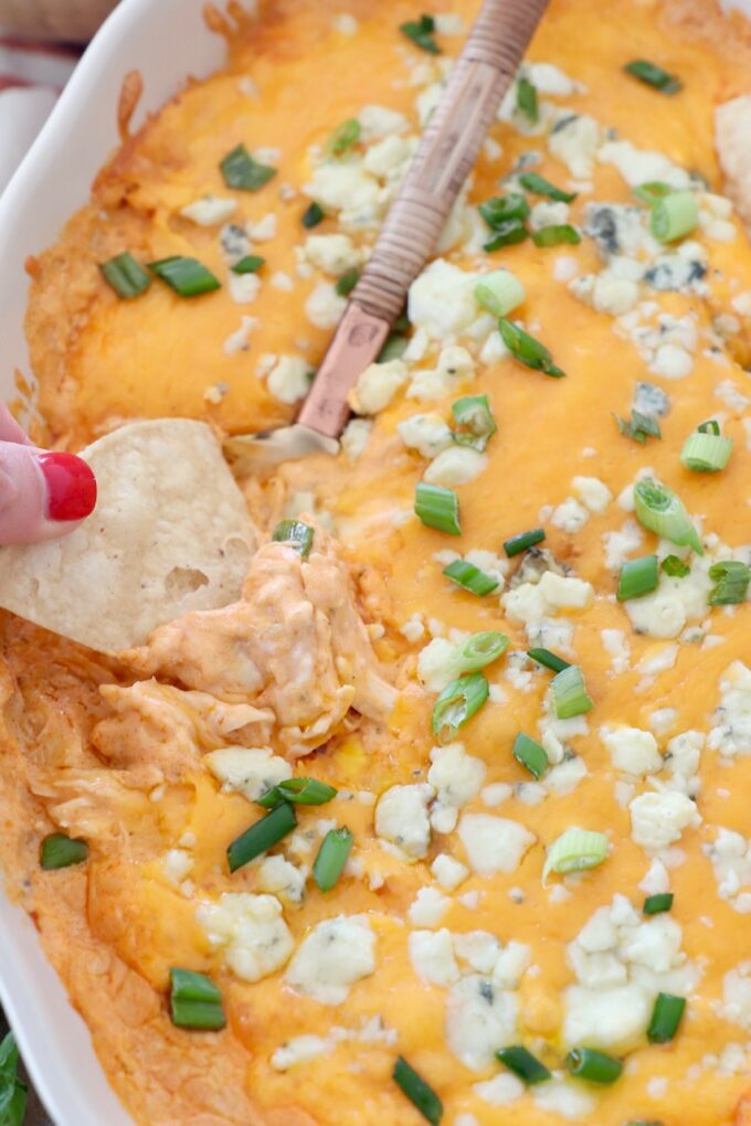 hand dipping tortilla chip into buffalo chicken dip