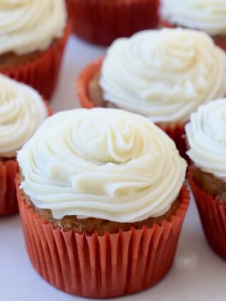 pumpkin cupcakes with frosting sitting on white plate