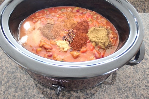 Seasonings atop chili in a slow cooker. 
