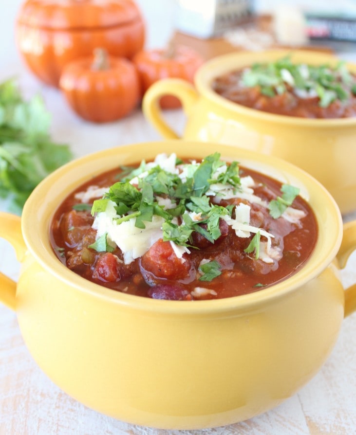 Yellow bowl filled with Pumpkin Chili garnished with melted cheese and cilantro.