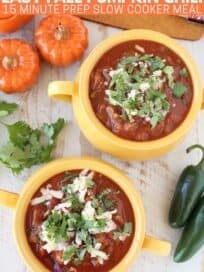Overhead image of pumpkin chili in yellow bowls topped with shredded cheese and cilantro