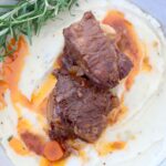 braised short ribs in bowl with mashed potatoes and fresh rosemary