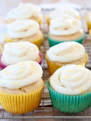 Lemon cupcakes with cream cheese frosting sitting on wire cooling rack