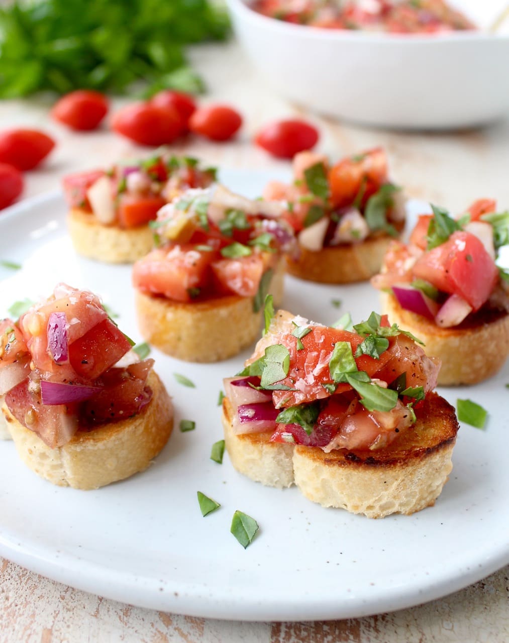 tomato bruschetta on plate, topped with fresh chopped basil