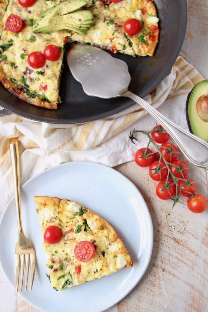 Slice of frittata on plate, next to frittata in skillet