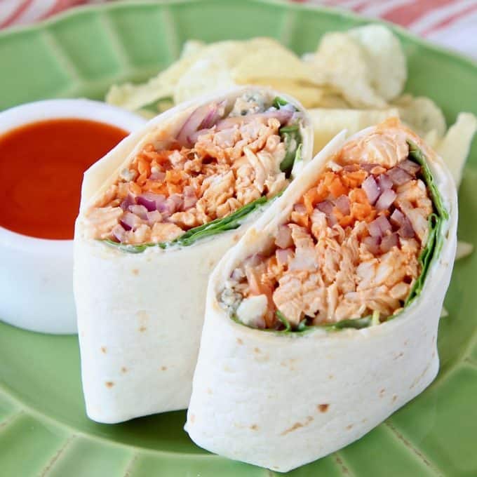 Buffalo chicken wrap, sliced in half, stood up next to each other on a green plate