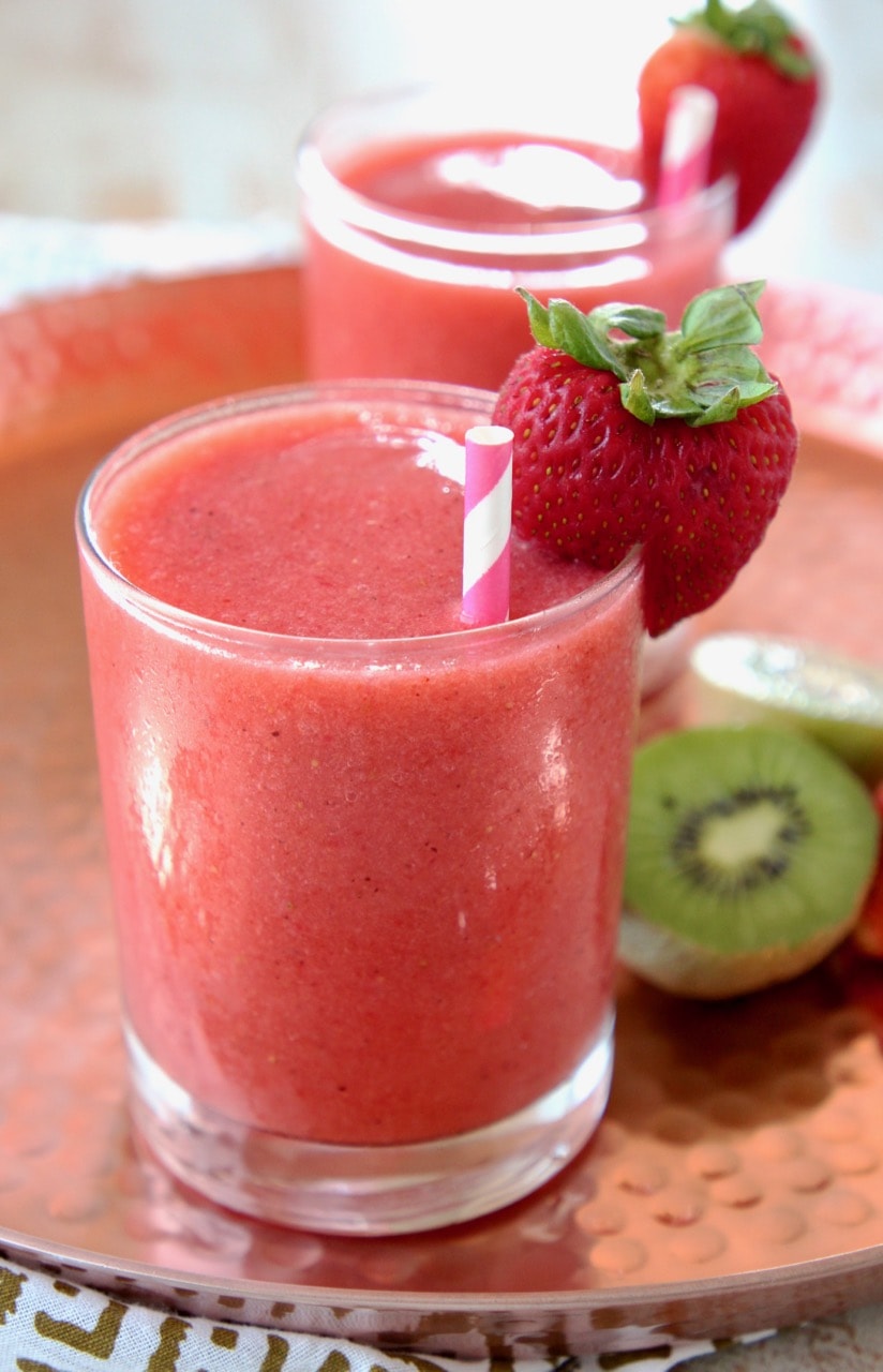 Strawberry kiwi slush in glass with pink and white striped straw