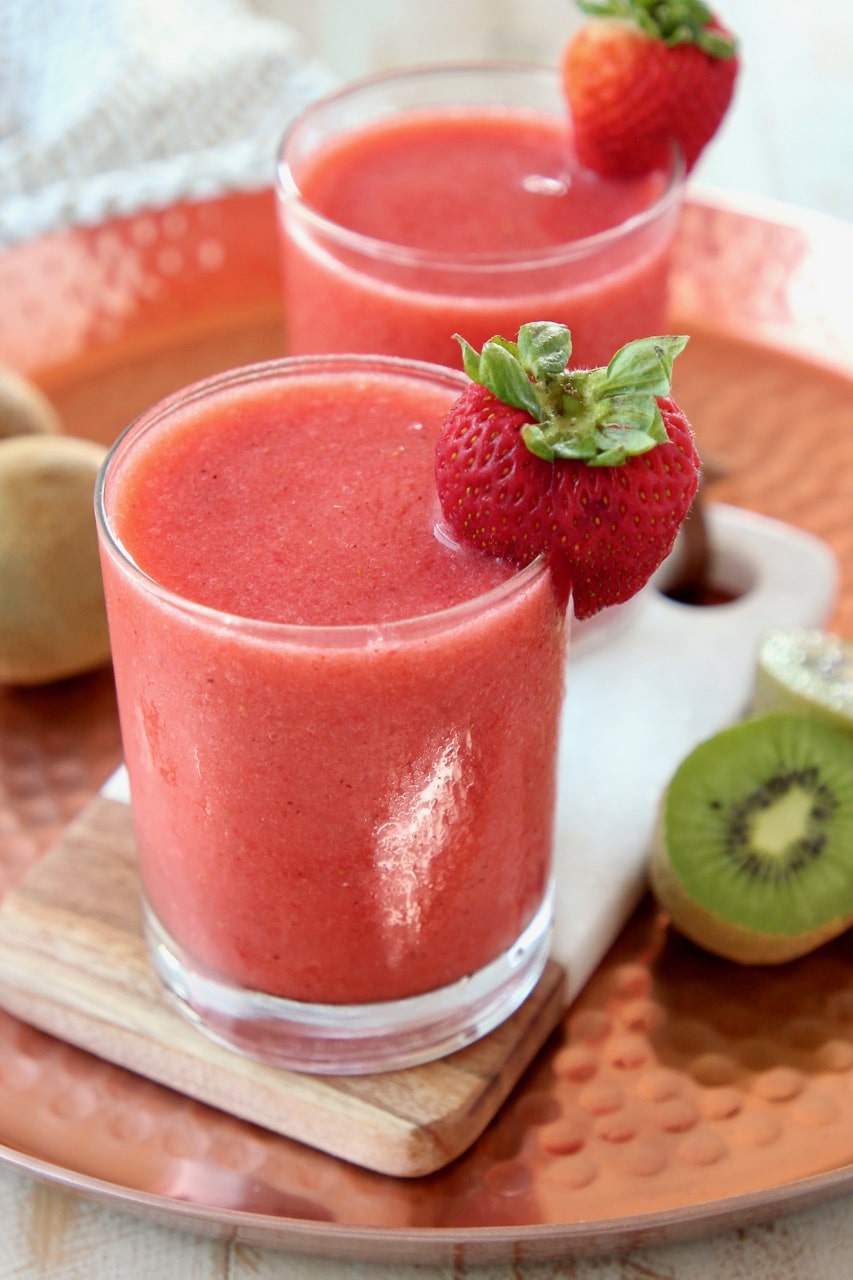 Strawberry slushie in glass with strawberry and kiwi on the side