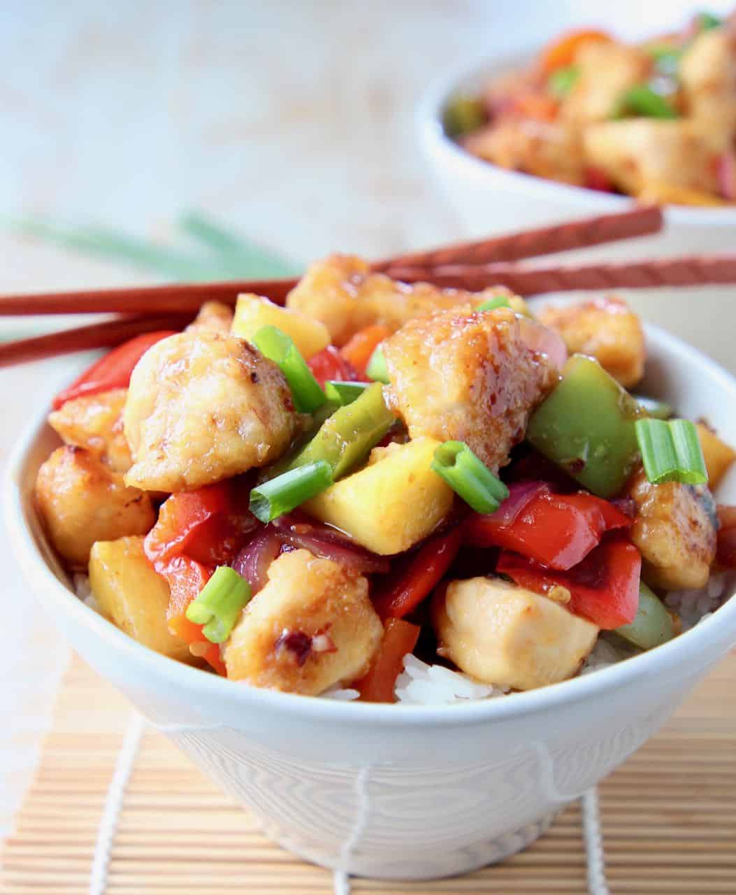Sweet and sour chicken in white bowl with chopsticks on the side