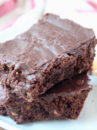 Two chocolate brownies stacked on top of each other on a plate