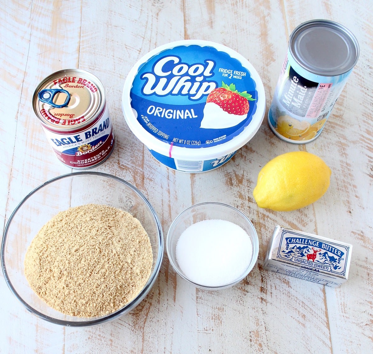 ingredients for frozen lemonade pie on a white wood board