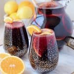 Red sangria in glasses and pitcher with sliced oranges
