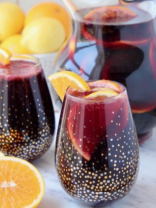 Red sangria in glasses and pitcher with sliced oranges