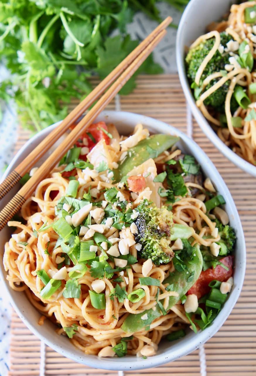 Noodles and vegetables in bowl with chopsticks on the edge of the bowl