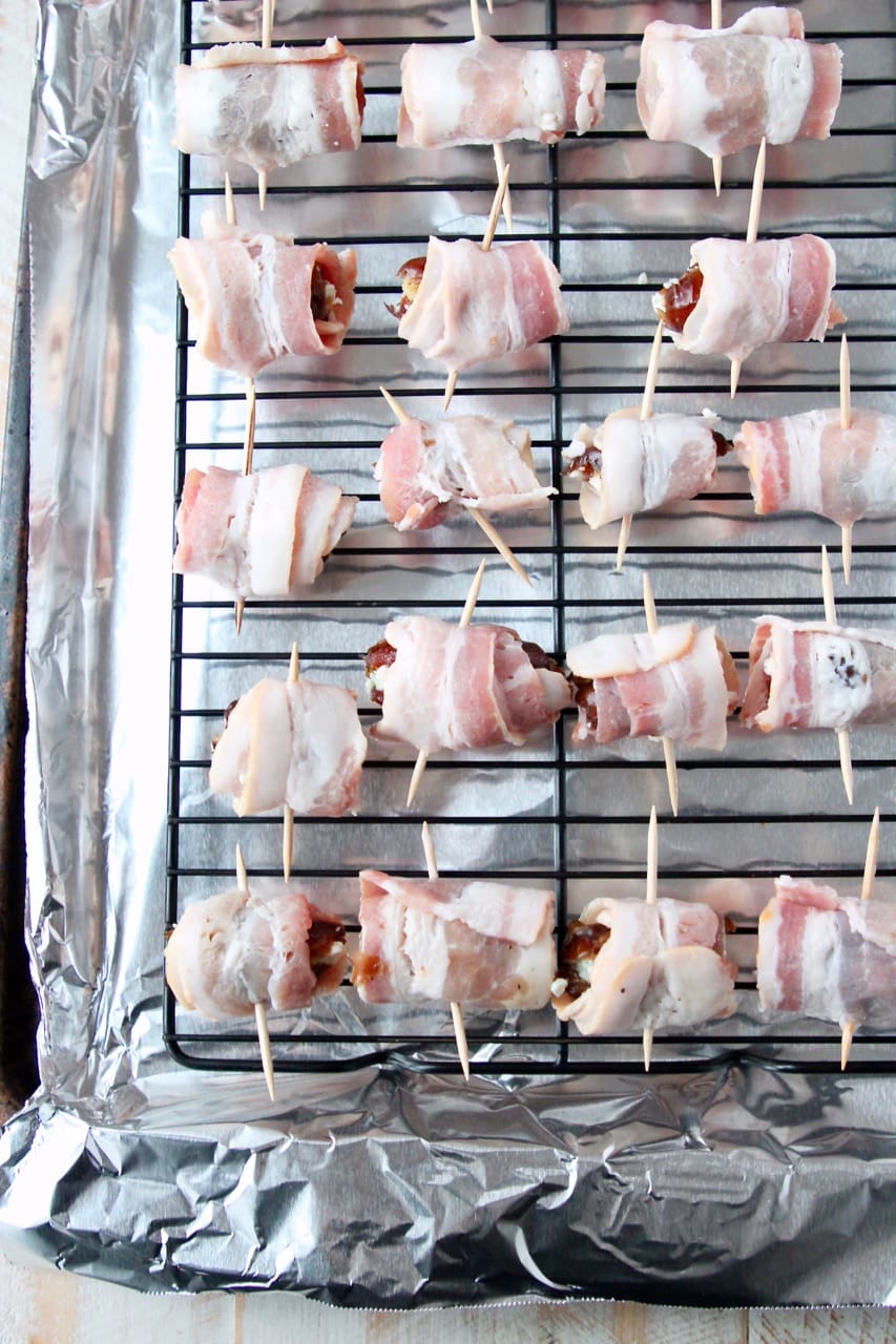 Uncooked bacon wrapped dates on baking sheet with foil