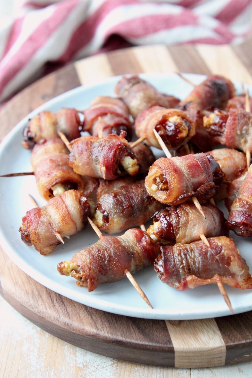 Bacon wrapped dates piled up on white plate
