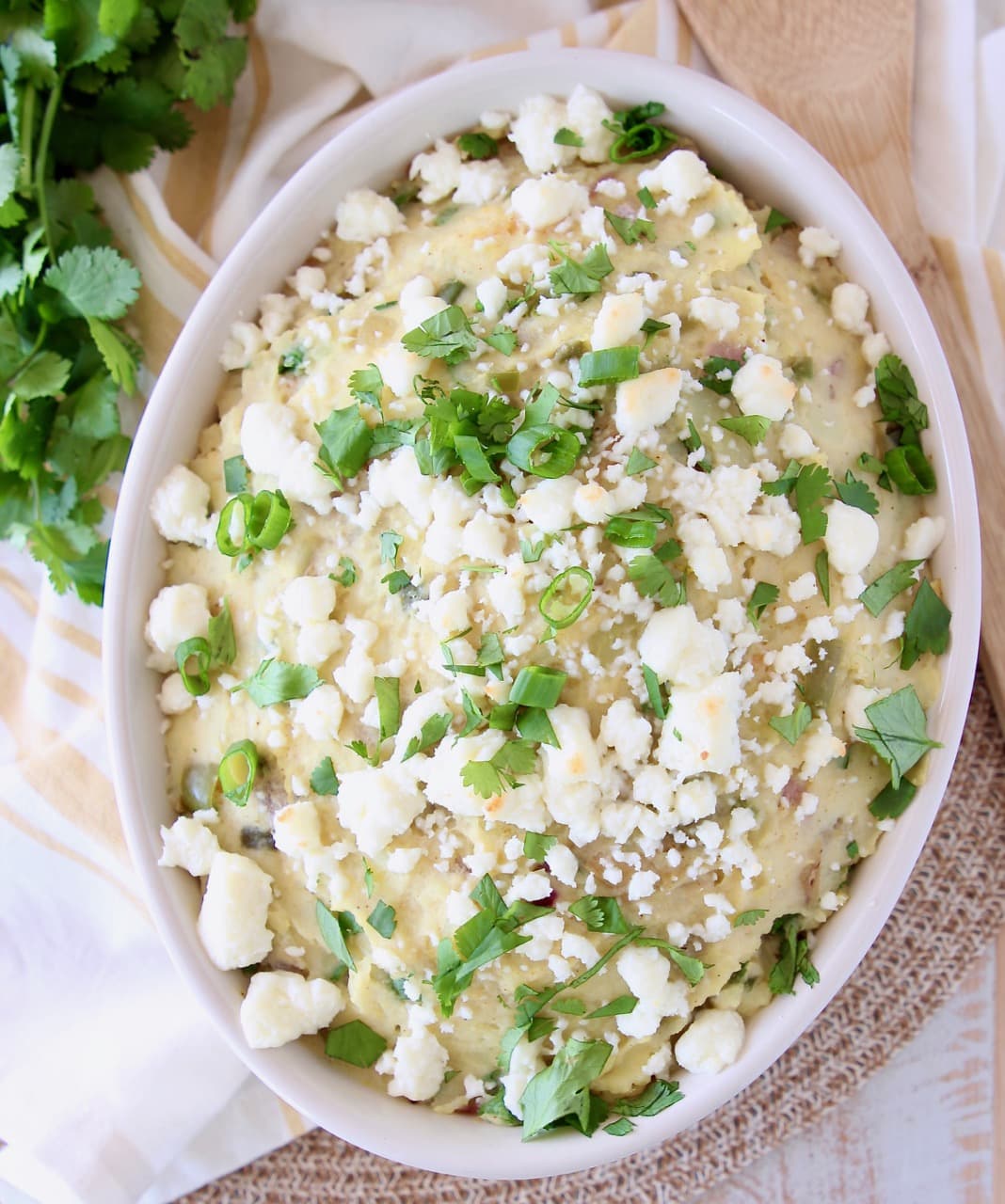 Bowl of mashed potatoes topped with queso fresco, cilantro and green onions