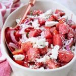 Diced watermelon and feta cheese crumbles in bowl with spoon