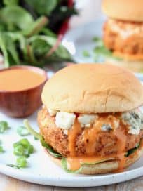 Chicken burger on bun with blue cheese crumbles and buffalo wing sauce