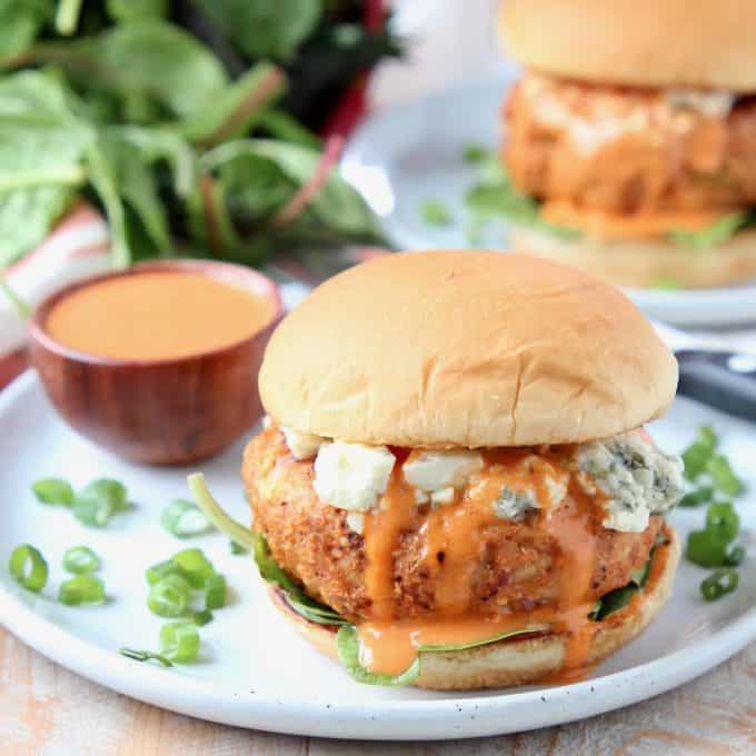 Chicken burger on bun with blue cheese crumbles and buffalo wing sauce