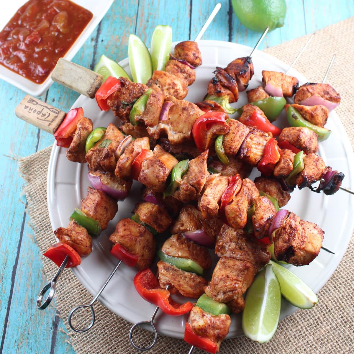 Grilled chicken fajita skewers on plate with lime wedges