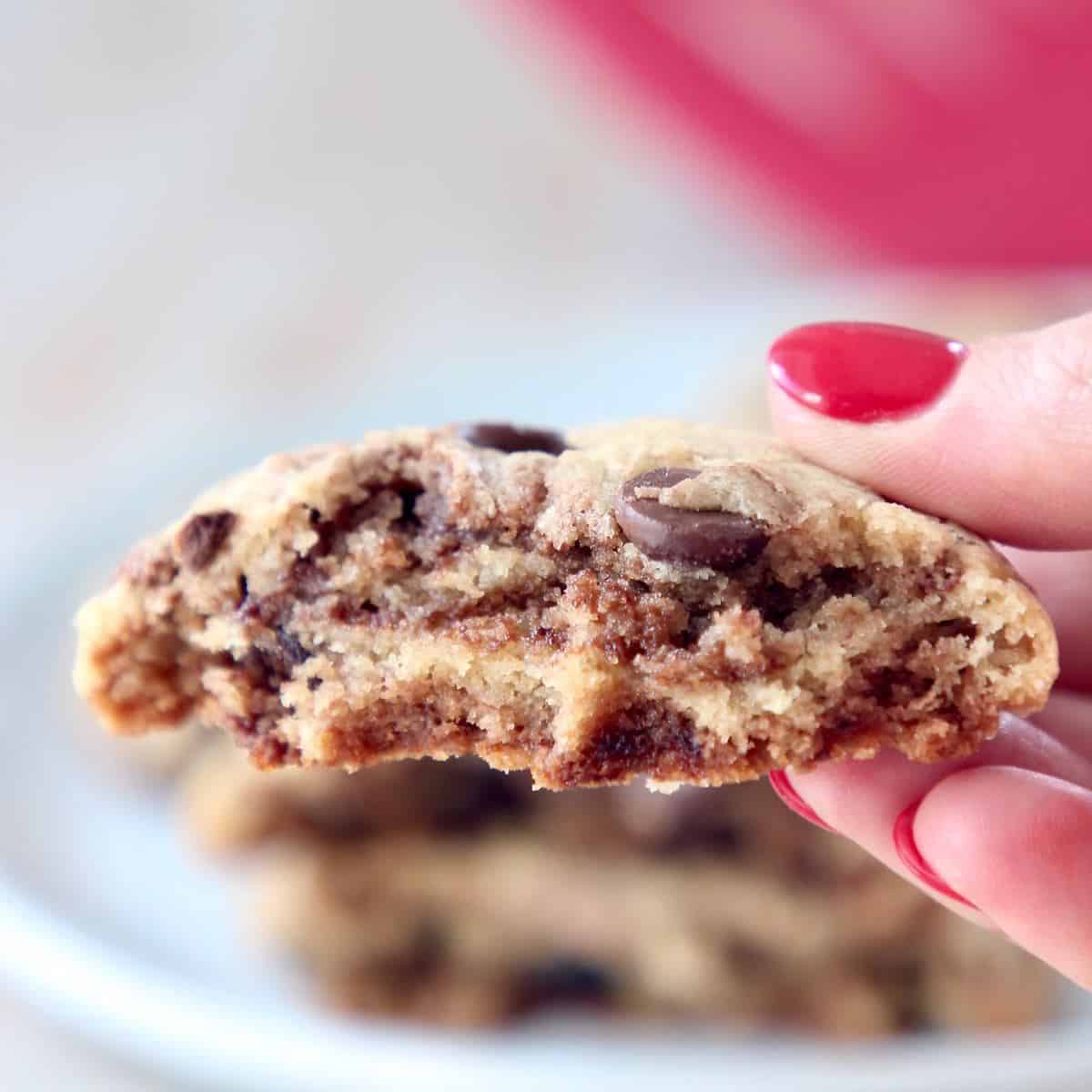 Hand holding half of a nutella chocolate chip cookie