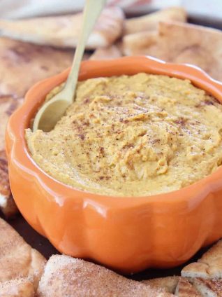 Pumpkin hummus in orange bowl with gold spoon