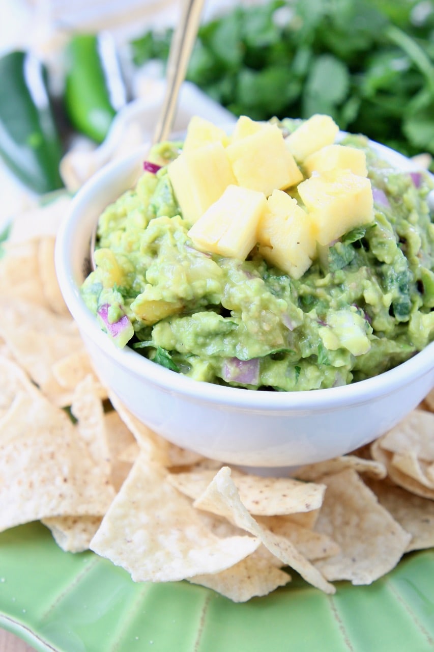 Pineapple guacamole in white bowl, surrounded by tortilla chips