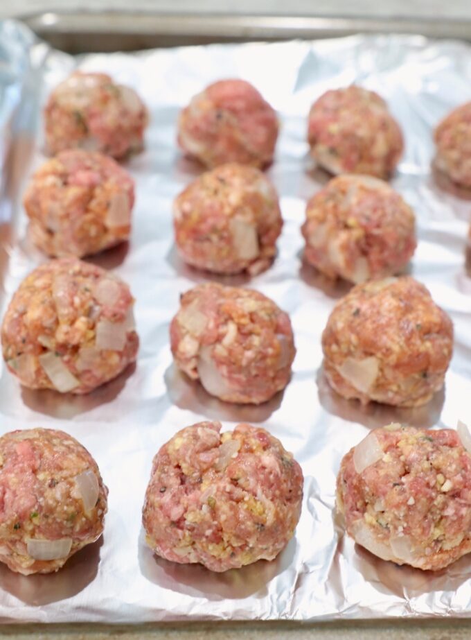uncooked Italian meatballs on foil lined baking sheet 