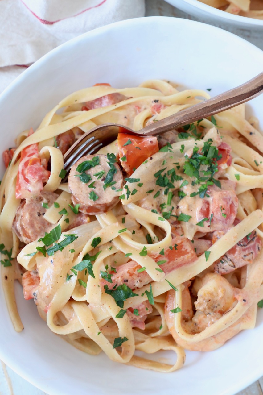 cooked cajun shrimp pasta with sausage in bowl with spoon