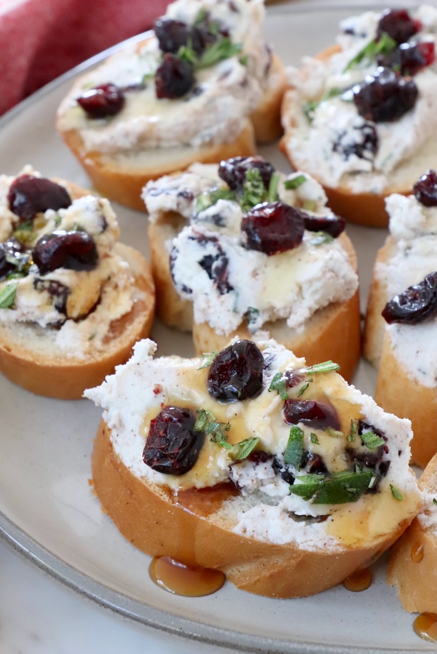 cranberry goat cheese crostini drizzled with honey on a plate