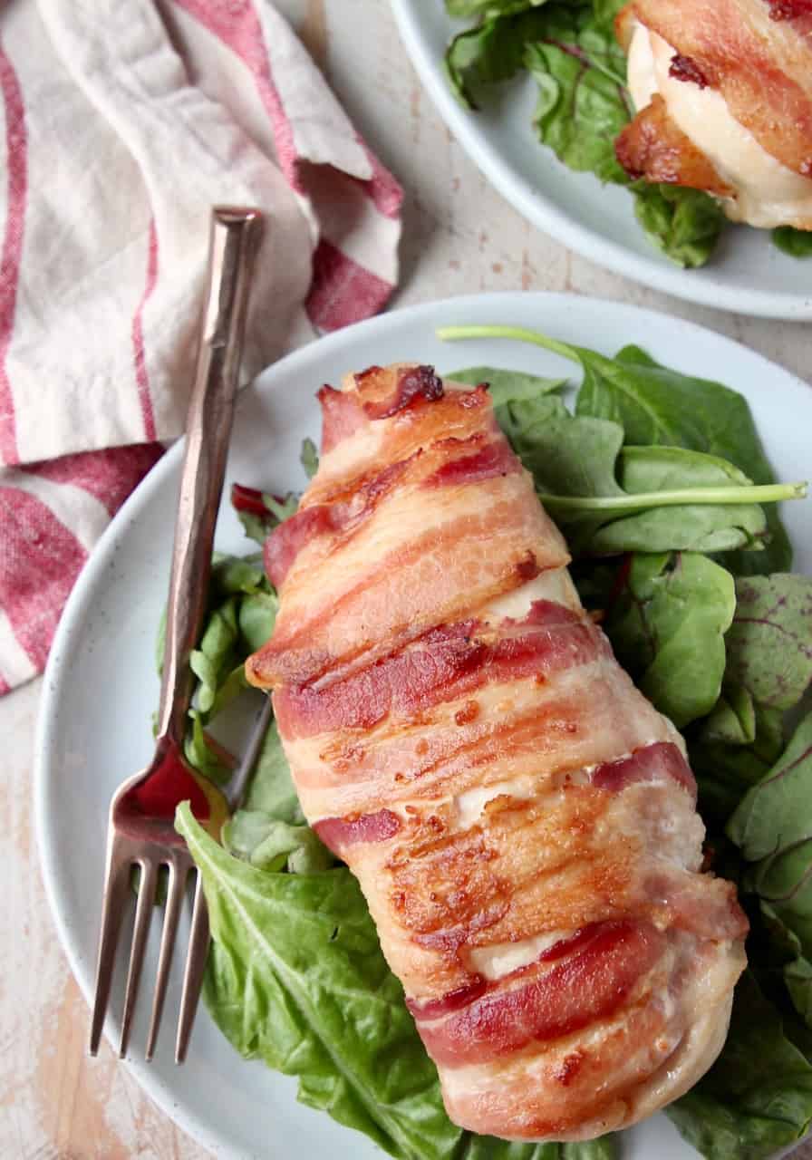 Bacon wrapped chicken breast on plate with fork and salad