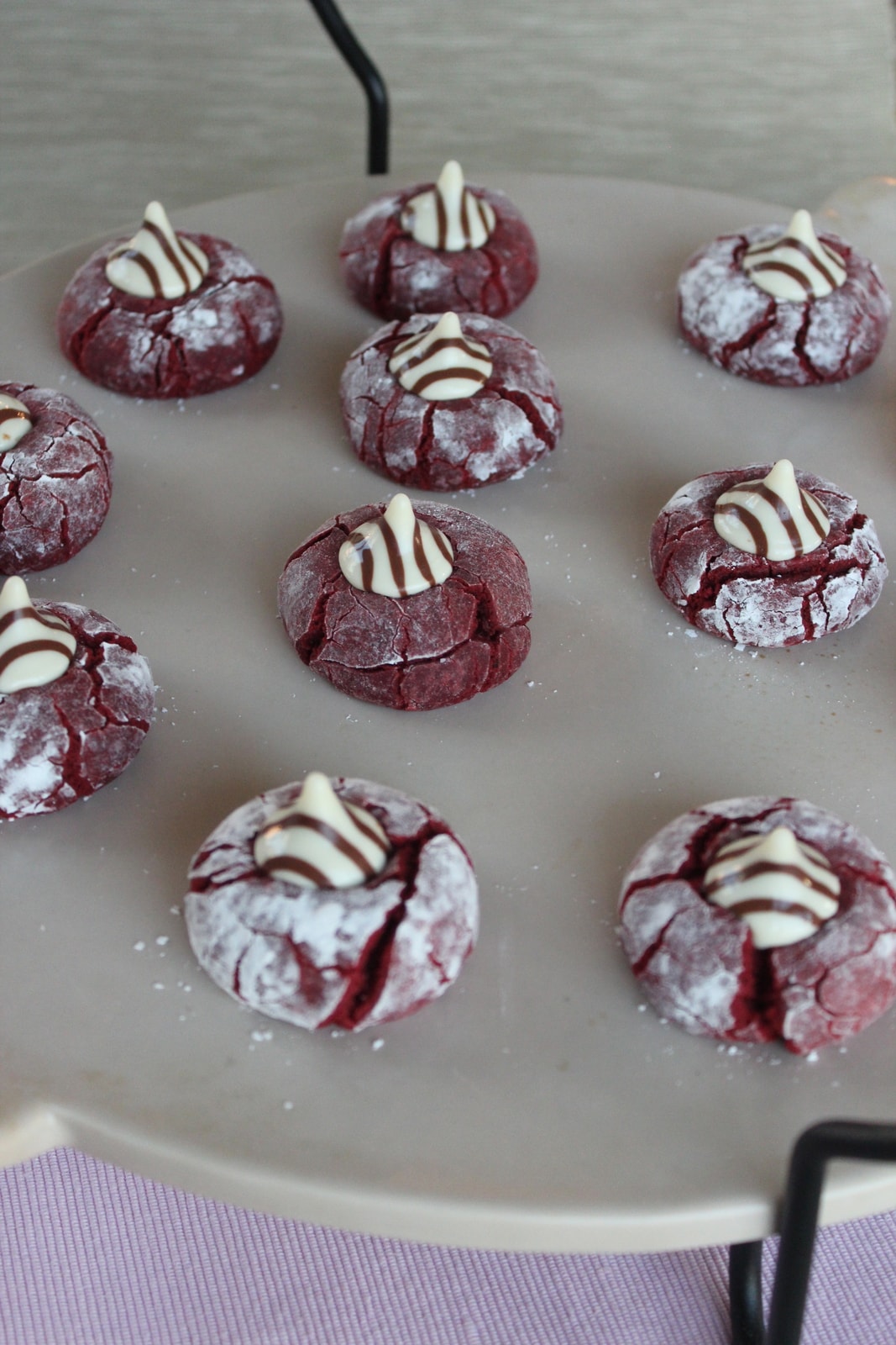 Red Velvet Cookies on a baking stone topped with hershey's hugs candies