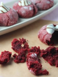 Red velvet cookie dough is rolled in powdered sugar to form a beautiful red and white crinkle cookie, topped with Hershey's hugs, these are the perfect Valentine's Day treat recipe.
