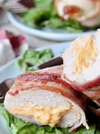 Bacon wrapped stuffed chicken breast cut in half on plate