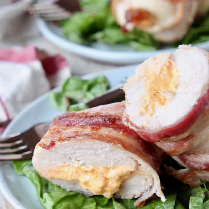 Bacon wrapped stuffed chicken breast cut in half on plate