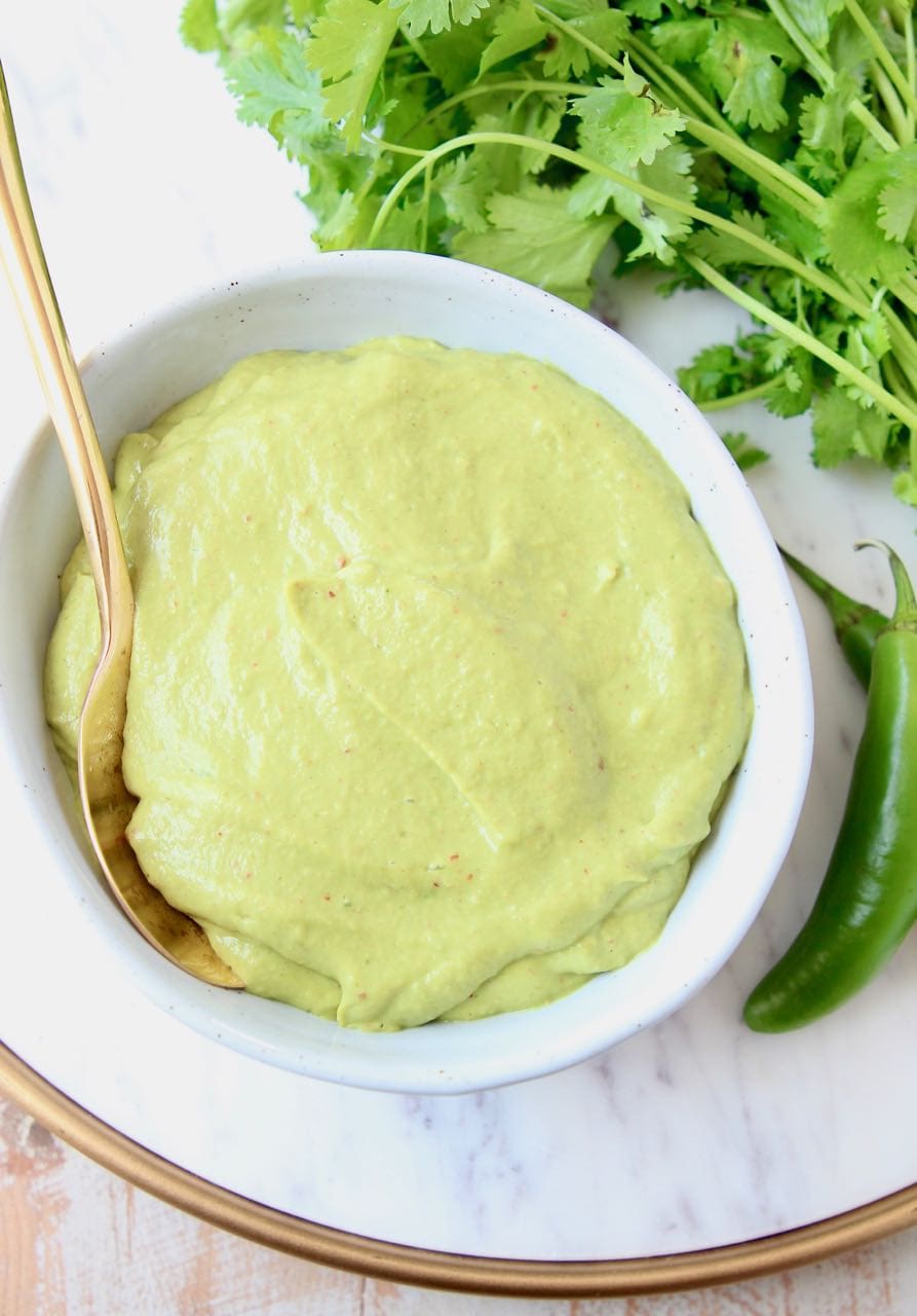 Creamy avocado sauce in bowl with gold spoon