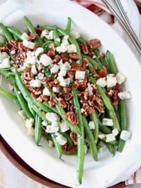 Overhead image of fresh green beans in serving bowl with pecans and blue cheese