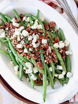 Overhead image of fresh green beans in serving bowl with pecans and blue cheese