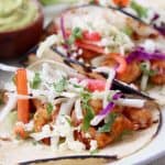 Grilled shrimp tacos in corn tortillas topped with slaw and cotija cheese