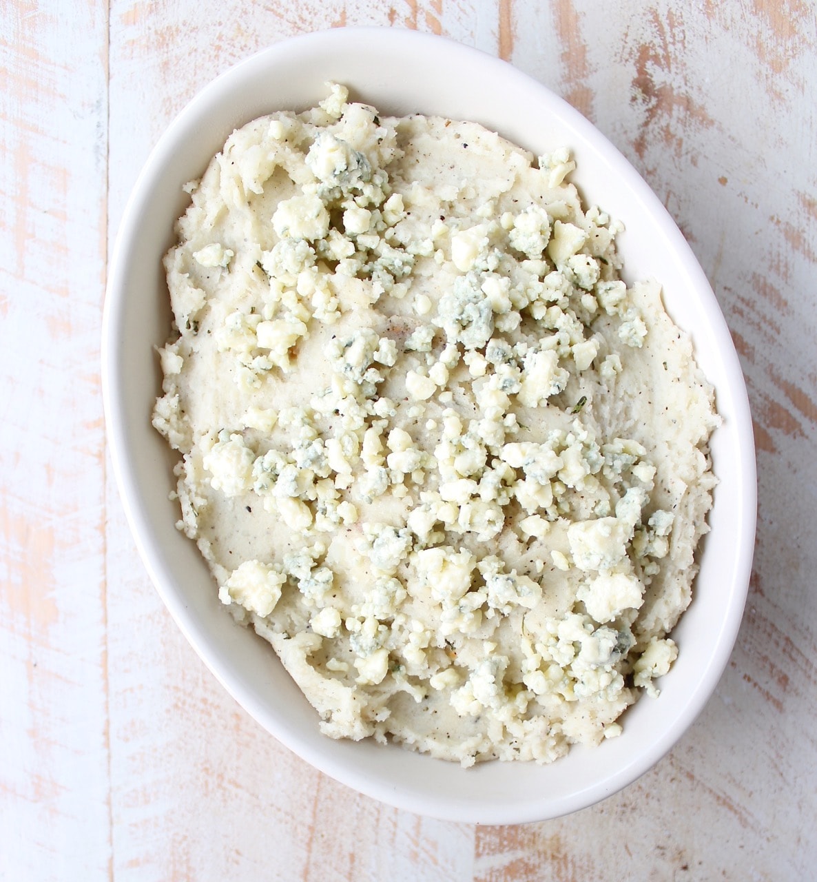 mashed potatoes in a bowl, topped with blue cheese crumbles