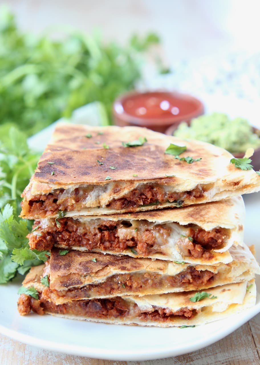 Soy chorizo quesadilla slices stacked up on a plate with fresh cilantro