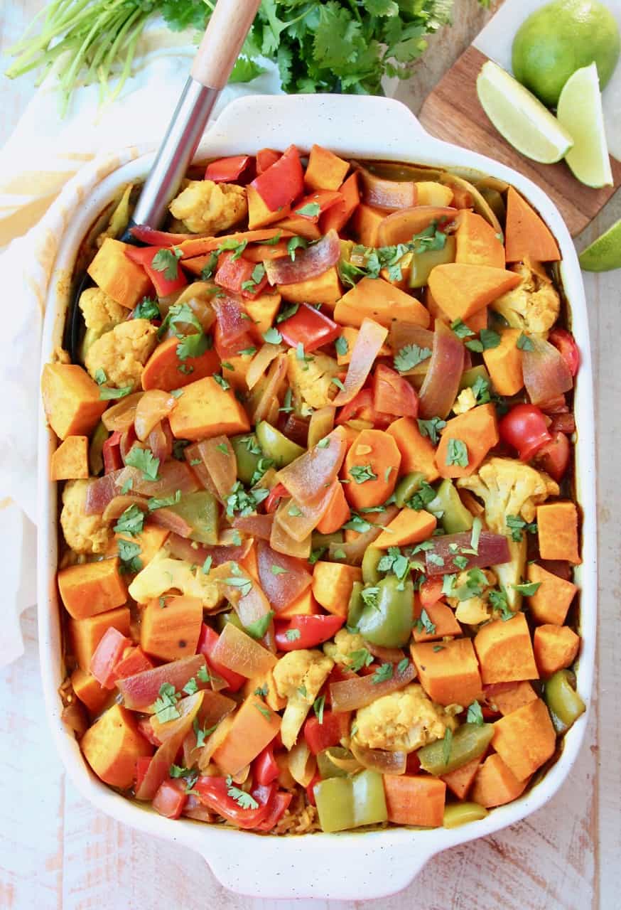 Overhead image of vegetable curry casserole in dish with serving spoon