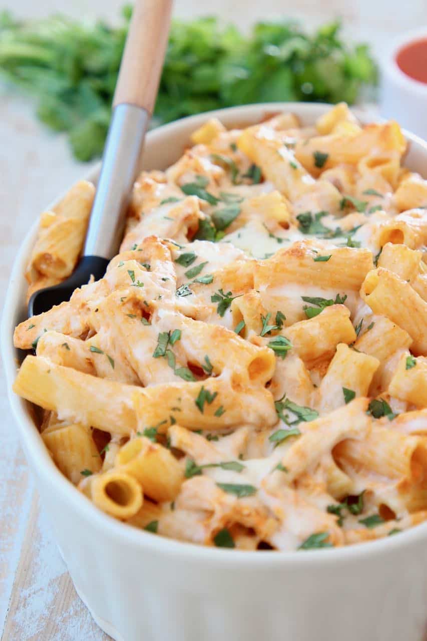 Buffalo chicken baked pasta in casserole dish with serving spoon