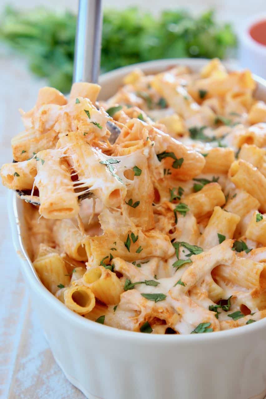 Baked cheesy pasta with spoonful coming out of baking dish