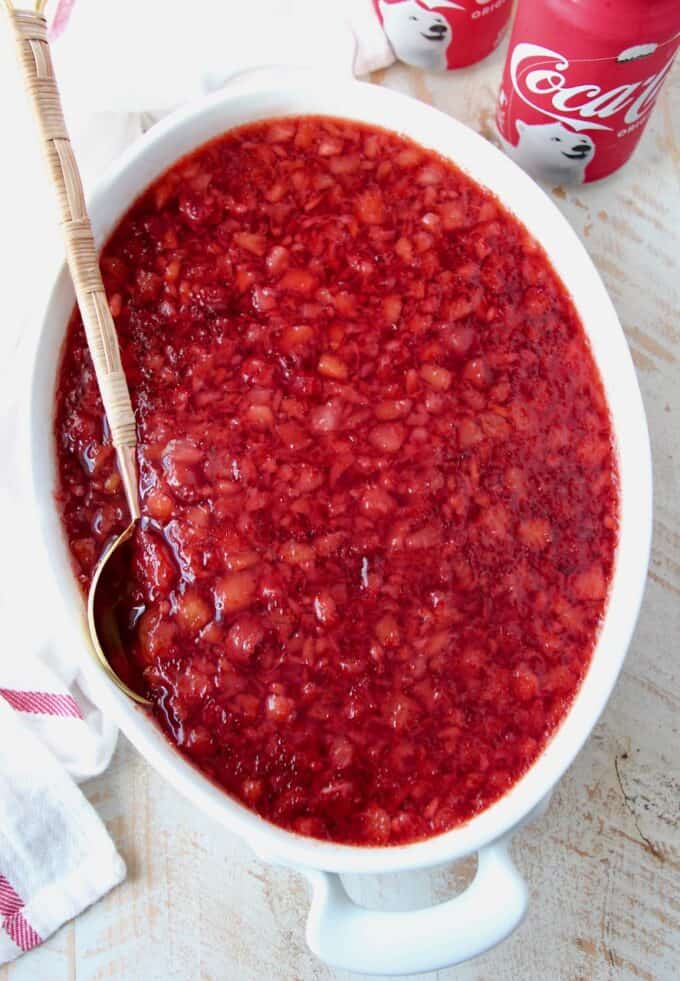 overhead image of cherry coke jello salad in white serving dish with spoon