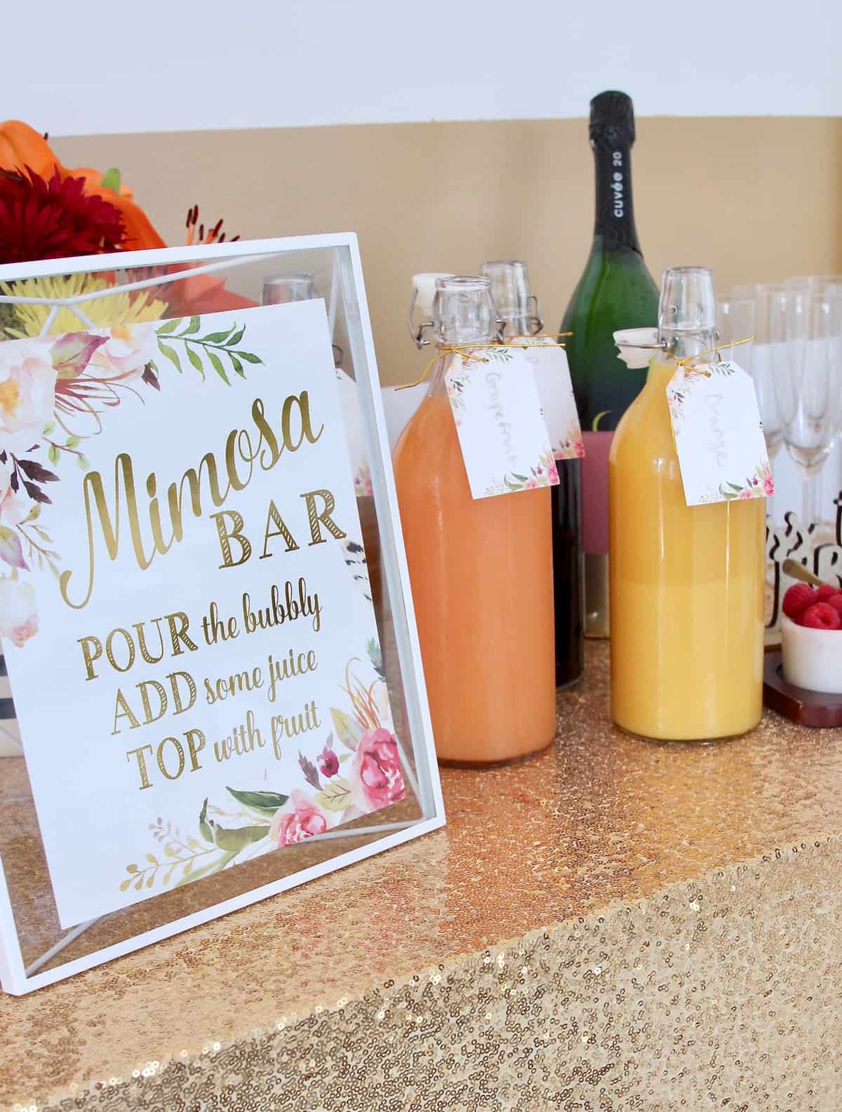 Mimosa bar sign and juices on bar with gold sparkly tablecloth
