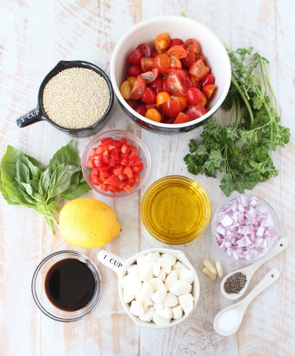 Quinoa Caprese Salad Recipe Ingredients in bowls on a wooden surface. 