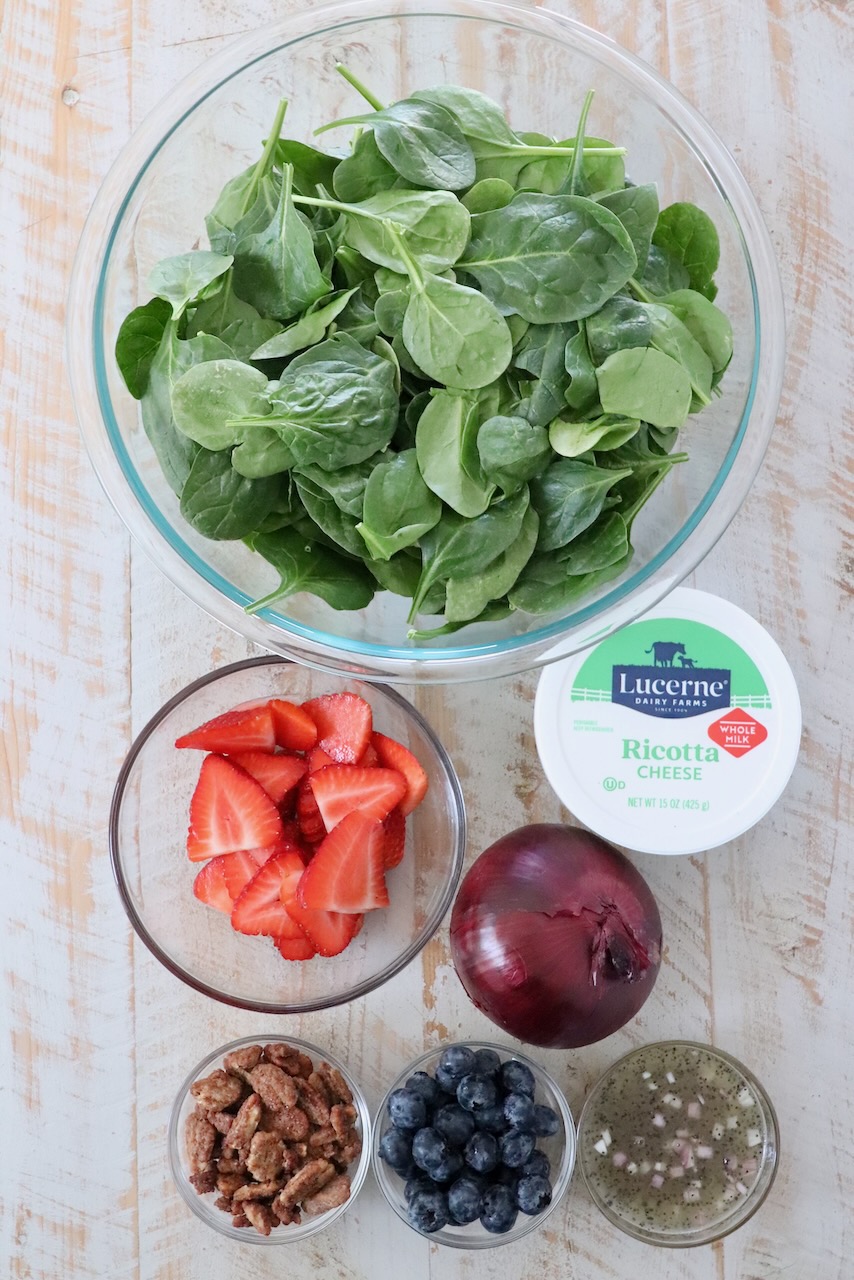 ingredients for spinach strawberry salad on white wood board